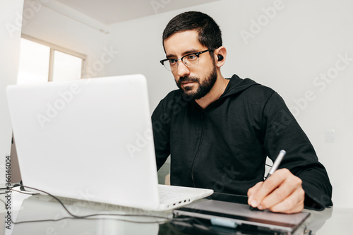 Designer working from home using laptop and tablet.