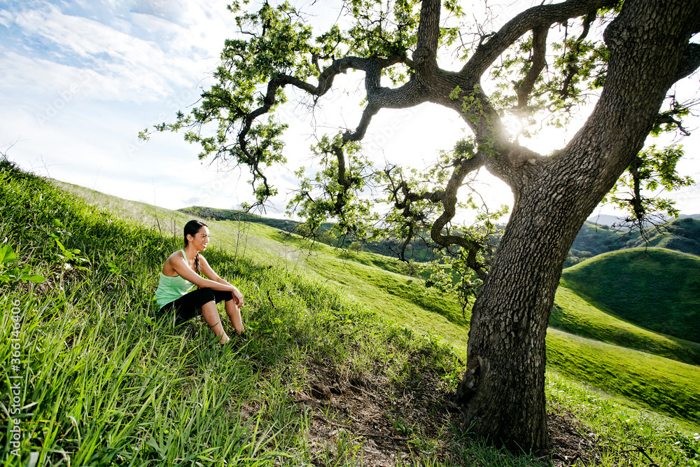 Mixed race athlete sitting on rural hillside Mixed race athlete sitting on rural hillside