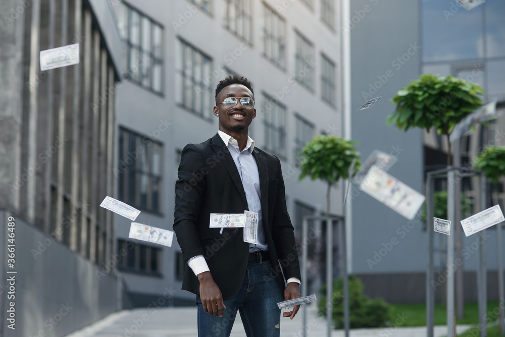 Smiling African man in suit throws the money at camera and sitting on bed in hotel room Smiling African man in suit throws the money at camera and sitting on bed in hotel room