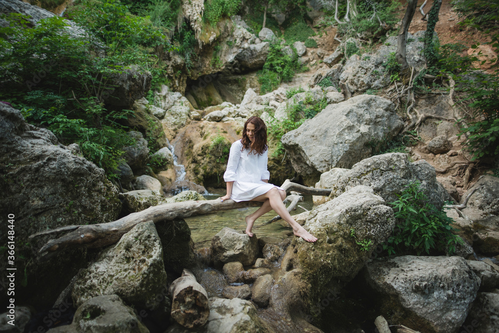 Ukraine, Crimea, Young woman sitting on branch over river in canyon Ukraine, Crimea, Young woman sitting on branch over river in canyon