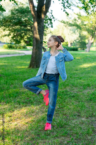 Girl in blue denim clothes posing in the park. © zerbob2