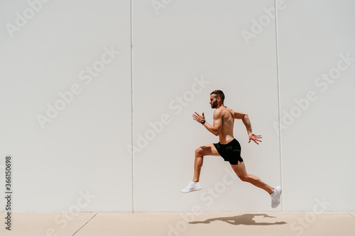 Barechested male athlete jumping at a wall photo