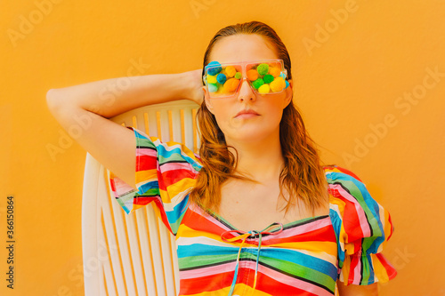 Portrait of woman wearing glasses with colourful pom poms covering her eyes