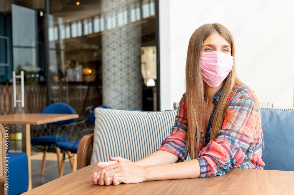 Woman wears mask in an empty cafe after coronavirus epidemic