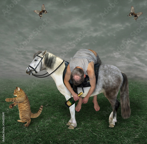Fotografie The drunk man with a bottle of champagne is lying across the horse saddle