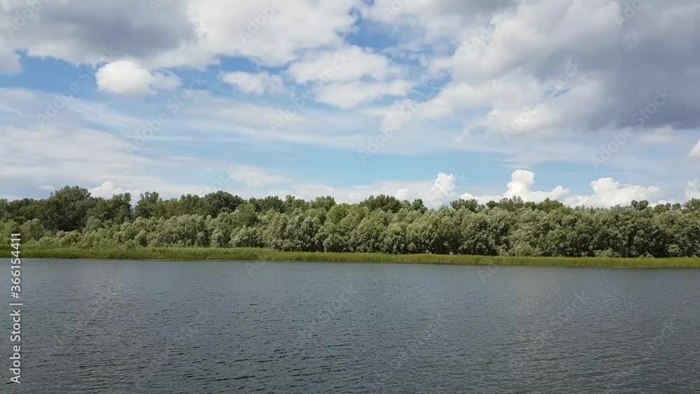 Beautiful summer landscape of the river. View from the river shore. Noon. The wind stirs the trees. Beautiful summer landscape of the river. View from the river shore. Noon. The wind stirs the trees.