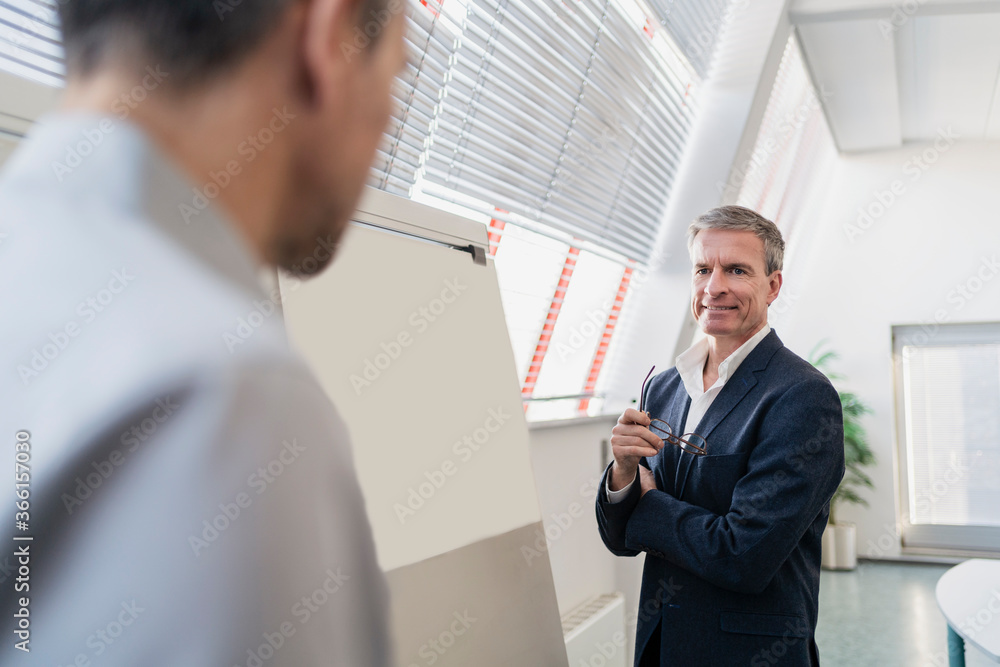 Smiling businessman looking at male coworker during meeting in office Smiling businessman looking at male coworker during meeting in office