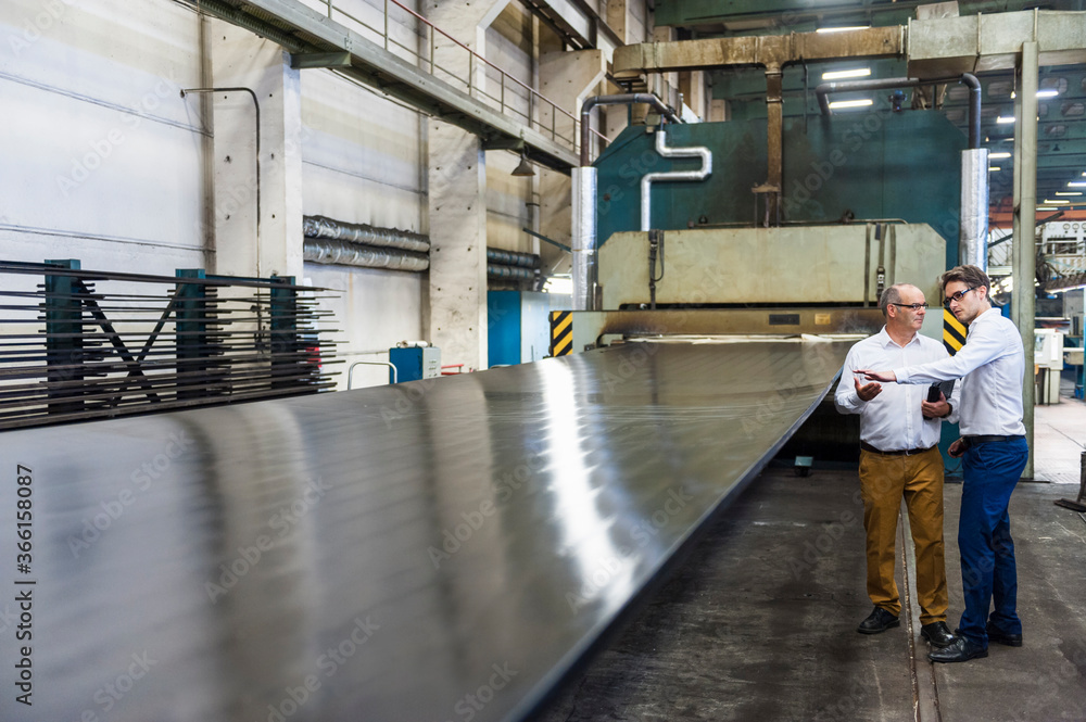 Two businessmen having a meeting in a factory hall Two businessmen having a meeting in a factory hall