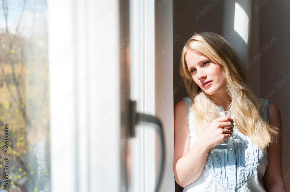 Portrait of serious blond woman looking out of window Portrait of serious blond woman looking out of window