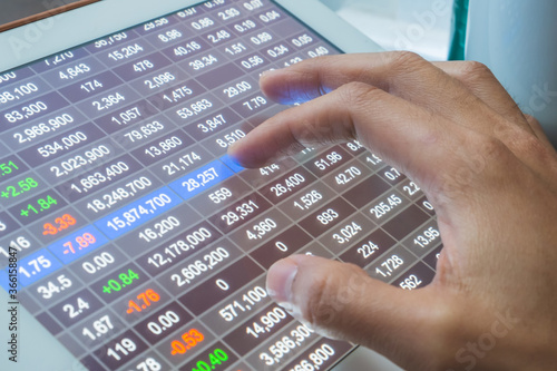 Close up shot of finger touching tablet screen selecting stock market.