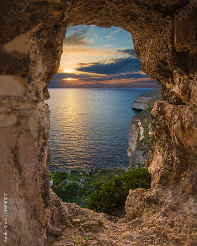 Sunset over Dingli Cliffs through the natural arch formation in the cliffs