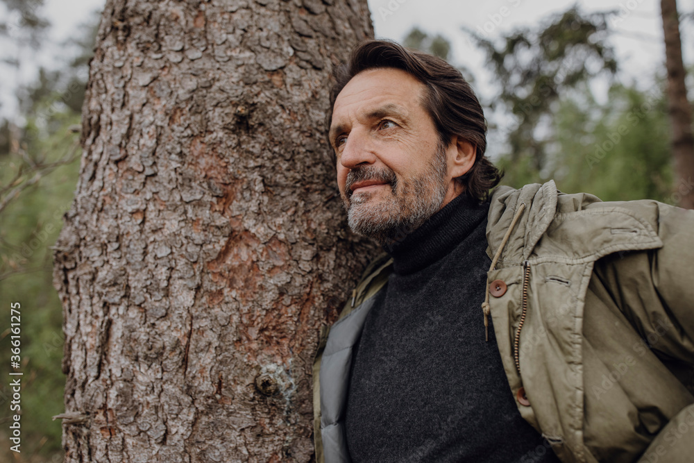 Mature hiker leaning on tree trunk Mature hiker leaning on tree trunk