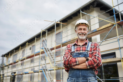 Smiling construction worker with crossed arms at construction site photo