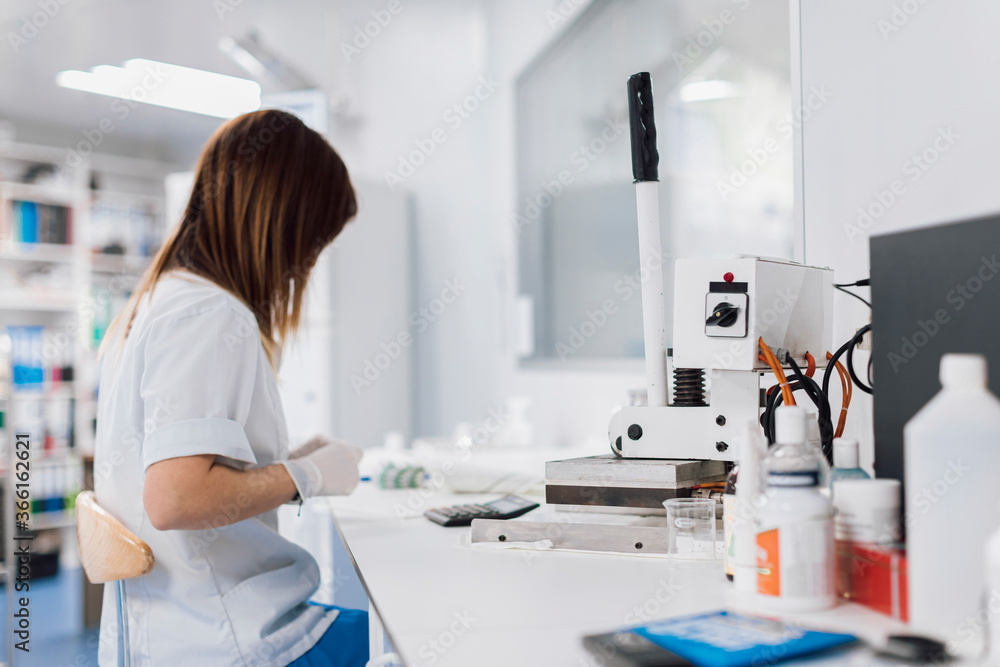 Side view of female doctor with long brown hair sitting at desk while working in laboratory Side view of female doctor with long brown hair sitting at desk while working in laboratory