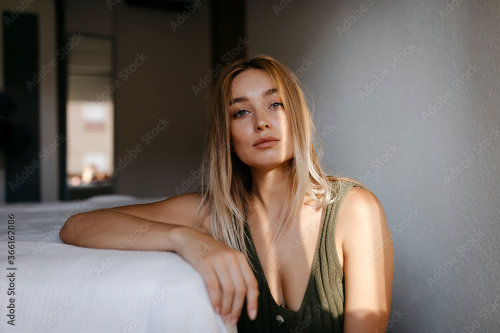 Seductive young woman sitting by bed in bedroom at home Seductive young woman sitting by bed in bedroom at home