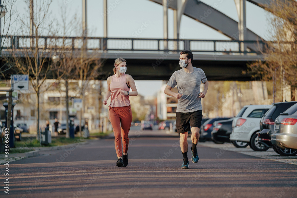 Young couple jogging on road in city during coronavirus