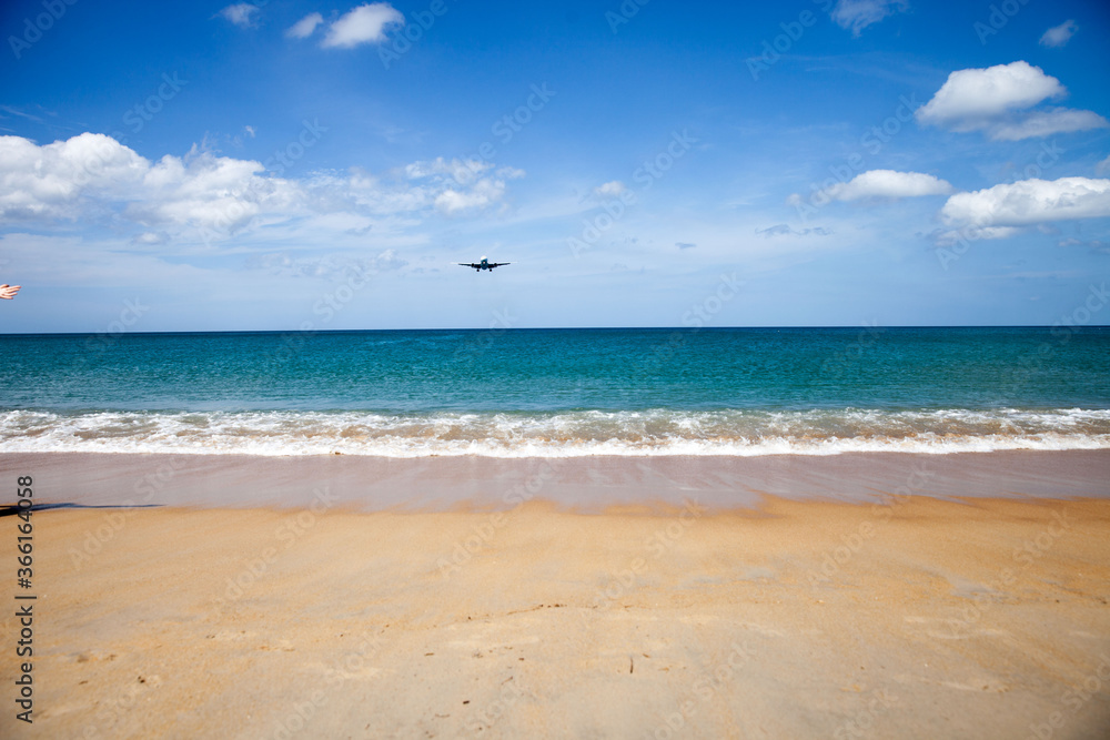 a passenger plane lands low over the sea, at an airport near the beach on a Sunny day