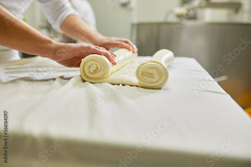 Cheese production, female worker rolling cheese, rolled layered cheese