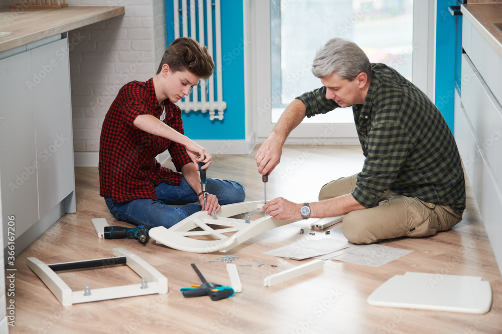 Obraz premium father and son work together. kitchen chair assembling