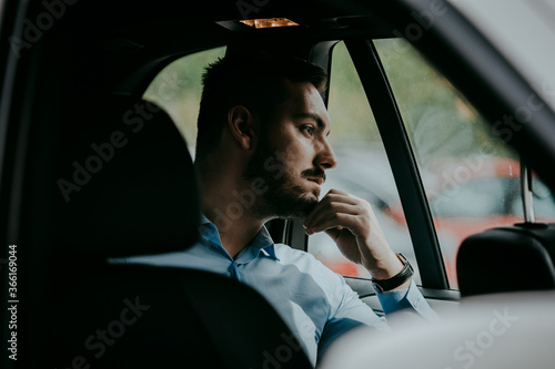 Man daydreaming in the backseat of a car 