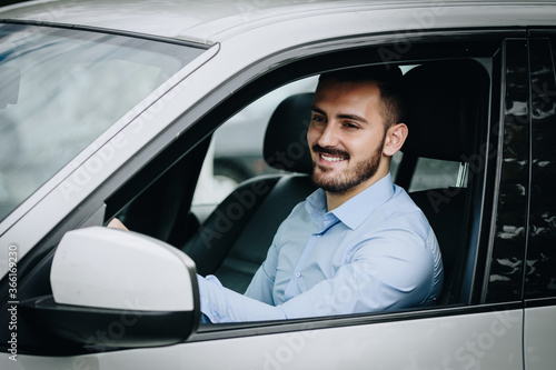 Formal looking man smiling while driving his car