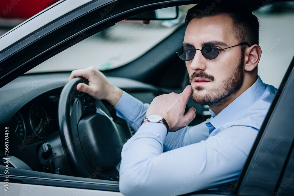 Handsome man with sunglasses sitting in luxury car posing Handsome man with sunglasses sitting in luxury car posing