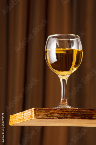 A glass of white wine on a vintage wooden bar counter with copy space. Shallow depth of field. Background blurred