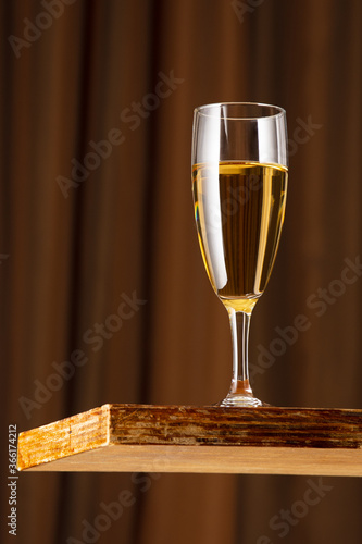 A glass of white wine on a vintage wooden bar counter with copy space. Shallow depth of field. Background blurred