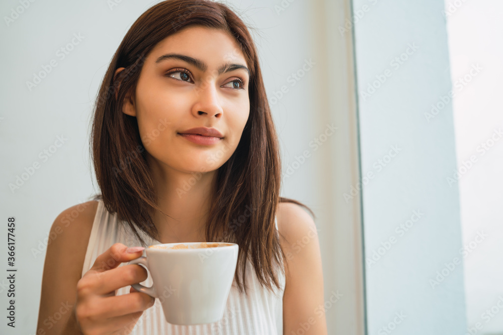 Young woman drinking a cup of coffee at coffee shop. Young woman drinking a cup of coffee at coffee shop.