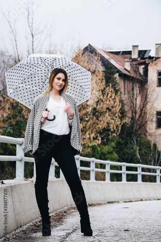 young fit woman in warm clothes posing for a picture with her umbrella outdoors © Denis
