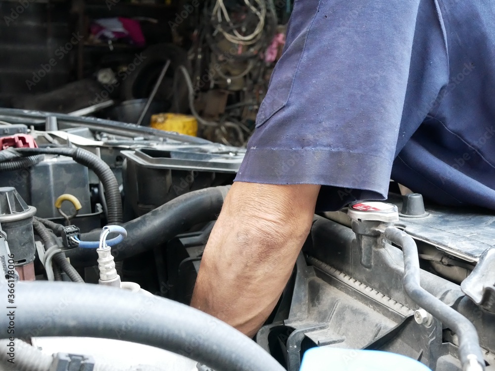 mechanic maintaining a car on engine room at garage. mechanic maintaining a car on engine room at garage.