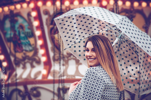 Woman enjoying her time at a amusement park holding an dotted umbrella