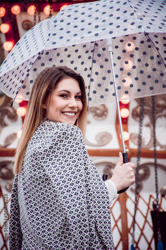 Cheerful woman holding an umbrella with dots at a carnival