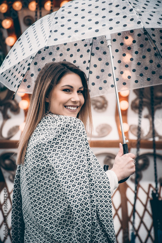 Cheerful woman holding an umbrella with black dots at a carnival
