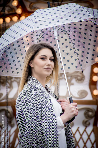 Young woman holding a dotted umbrella at a carnival