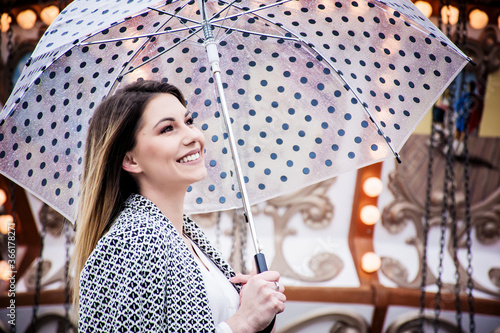 Cheerful woman holding a dotted umbrella at a carnival