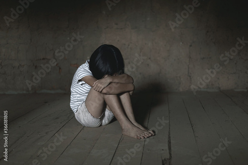 Helpless child sitting on floor against old earth brick wall,children violence and abused concept,human trafficking concept