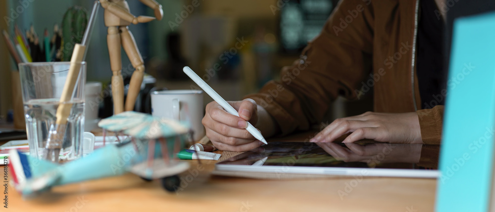 Female college student doing assignment with digital tablet, books and supplies on wooden table Female college student doing assignment with digital tablet, books and supplies on wooden table