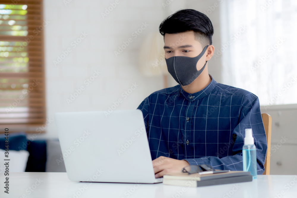 Young business man in face mask working from home with laptop computer on desk for protection for outbreak of covid-19 and healthcare, male quarantine stay home using notebook on desk, new normal. Young business man in face mask working from home with laptop computer on desk for protection for outbreak of covid-19 and healthcare, male quarantine stay home using notebook on desk, new normal.