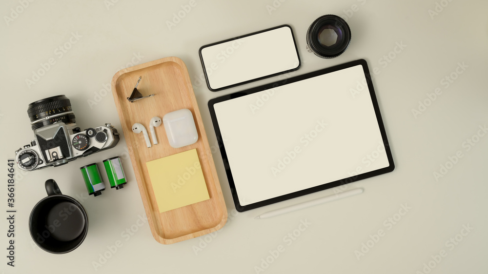 Photographer worktable with mock up tablet, smartphone, camera, earphone and supplies on white desk