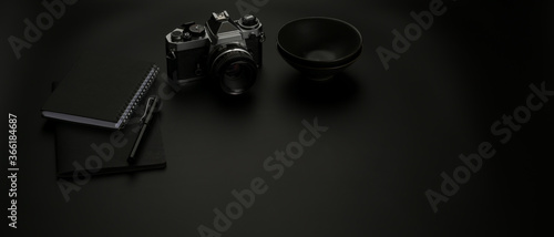 Dark worktable with copy space, camera, schedule books and black ceramic bowl on black table