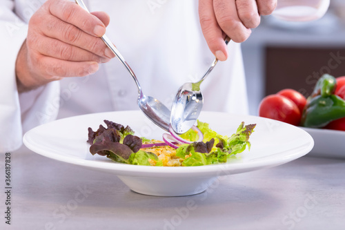 Male chef putting onion slices on a salad