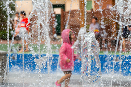 children cooling off in the fountain of the square(Blurry background with focus on fountains)