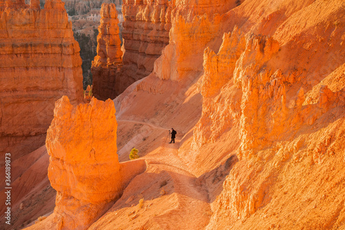 A photographer on a trail in Bryce Canyon National Park, Utah. The park features a collection of giant natural amphitheaters and is distinctive due to geological structures called hoodoos.