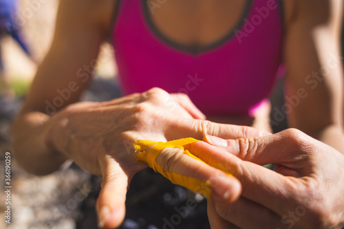 Rock climber bandages his fingers with a protection tape.