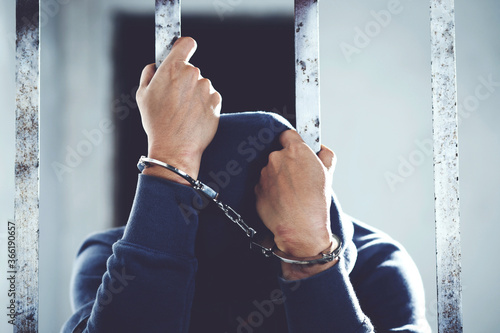 Fotografie male criminal standing handcuffs lock in prison cage. Offender
