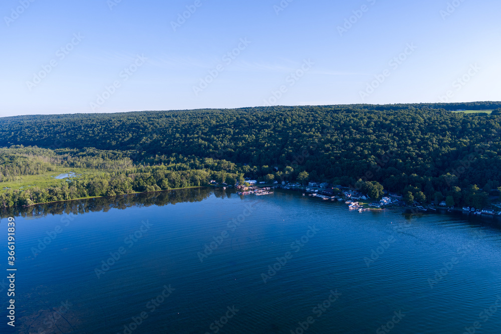 Late afternoon sun shines on Owasco Lake near Moravia, Cayuga County, New York. A small marina is in the center.