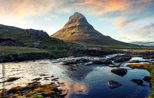 Amazing picturesque landscape with colorful sky of Iceland during sunset. Impressive view on famous majestic Kirkjufell mountain with reflection. Iconic location for photographers. Travel to Iceland.