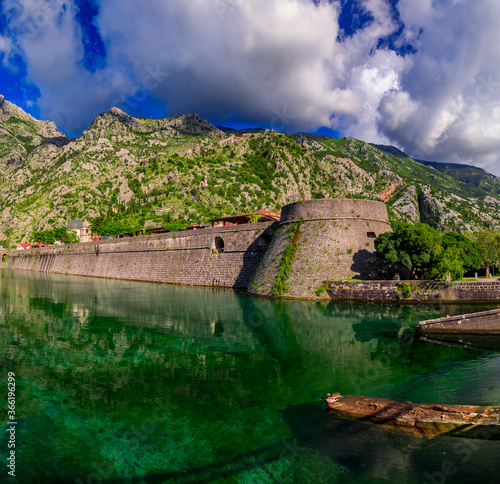 Emerald green waters of Kotor Bay or Boka Kotorska  mountains and the ancient stone city wall of Kotor old town former Venetian fortress in Montenegro