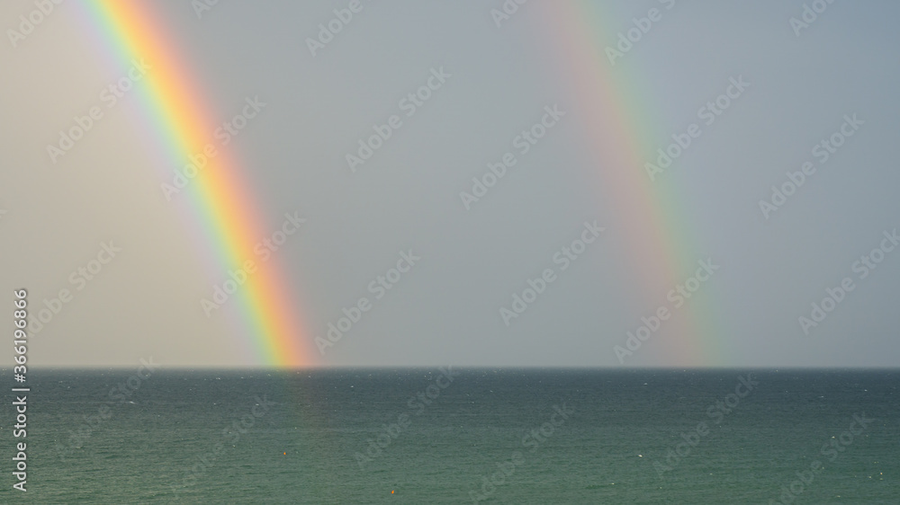 Wonderful double rainbow over the Adriatic sea. Contrast between the bright colors of the rainbow and the green sea Wonderful double rainbow over the Adriatic sea. Contrast between the bright colors of the rainbow and the green sea
